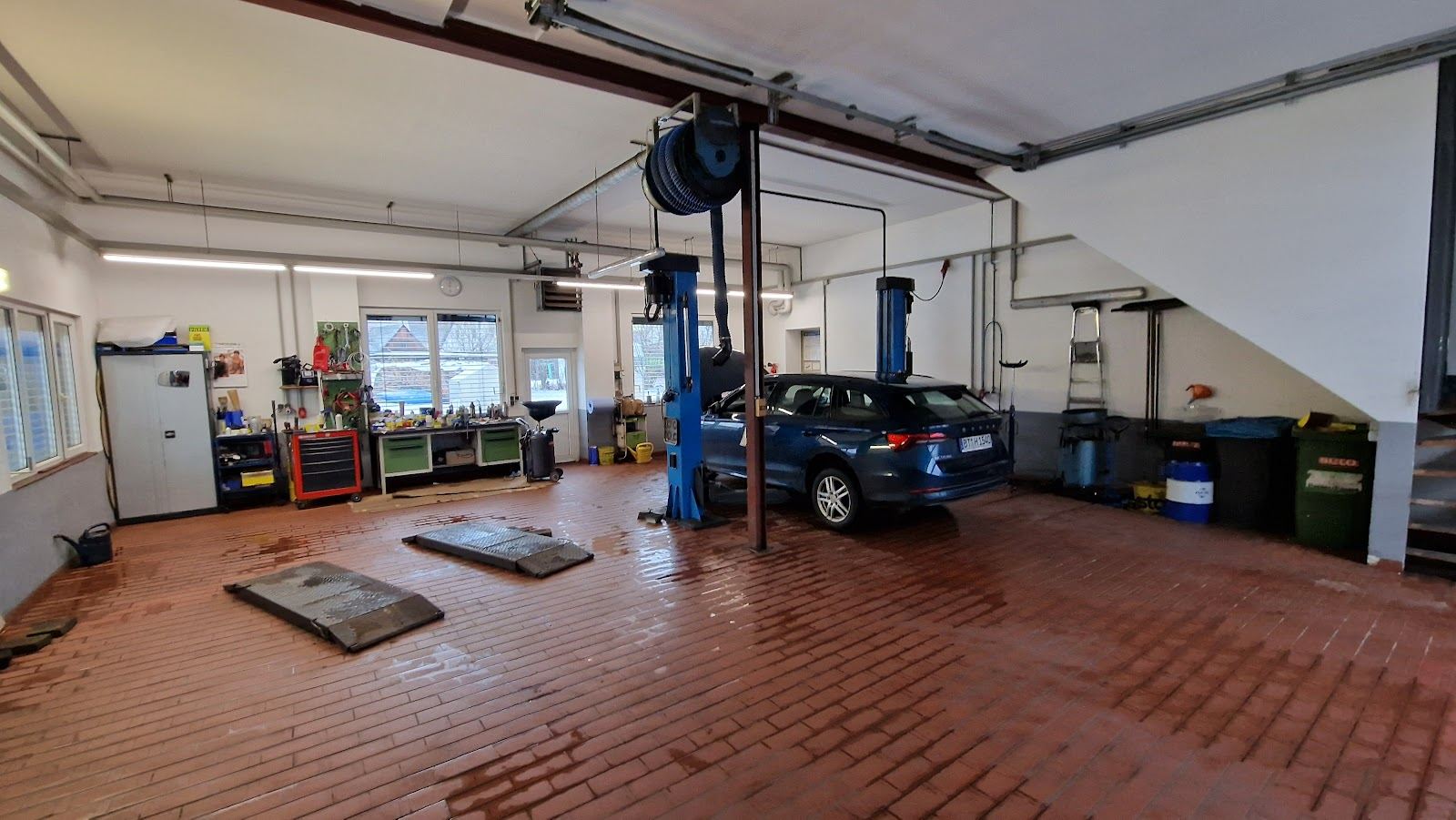 Blick in die Werkstatthalle von Auto Scharrer: Hebebühne, Fahrzeug, aufgeräumte Werkbank