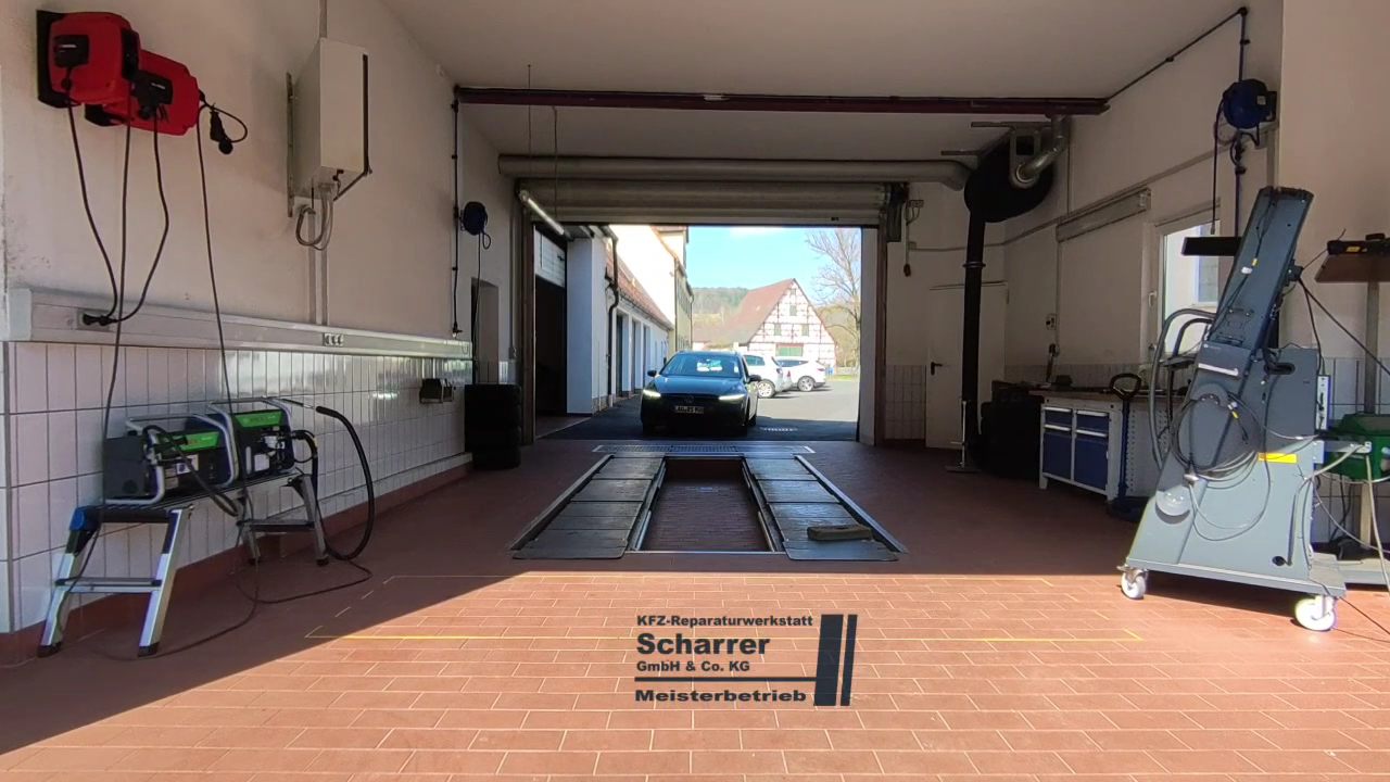 Blick durch das offene Werkstatttor auf den Hof und die Fachwerkhäuser von Aspertshofen